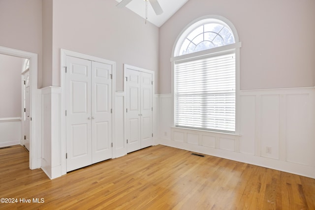 unfurnished bedroom featuring ceiling fan, light hardwood / wood-style floors, and two closets