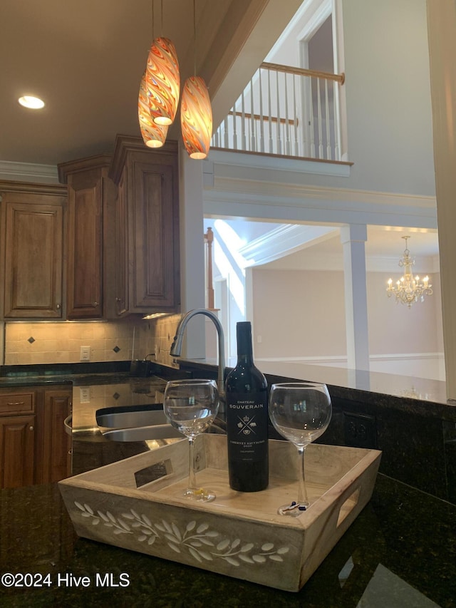 kitchen with sink, hanging light fixtures, an inviting chandelier, decorative backsplash, and ornamental molding