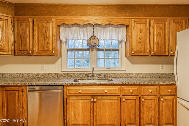 102 James Creek Rd, Southern Pines, NC 28387 - kitchen with stainless steel dishwasher, a sink, freestanding refrigerator, brown cabinets, and light stone countertops