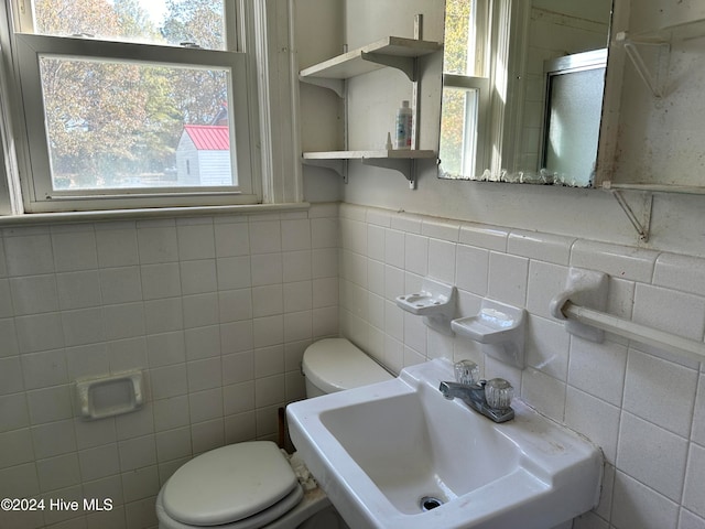 bathroom with tile walls, a healthy amount of sunlight, and sink