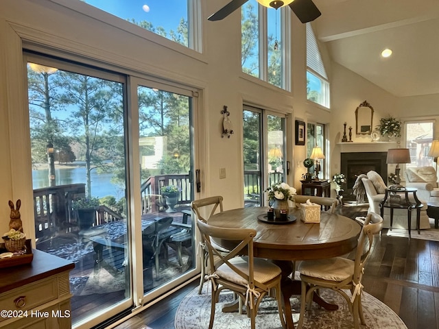 dining area with high vaulted ceiling, dark hardwood / wood-style floors, ceiling fan, and a water view