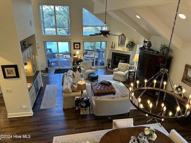 living room with plenty of natural light, a towering ceiling, dark wood-type flooring, and ceiling fan