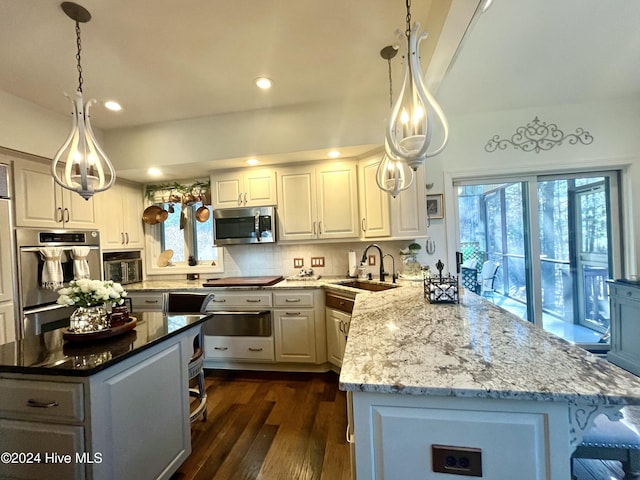 kitchen with sink, white cabinetry, hanging light fixtures, stainless steel appliances, and decorative backsplash