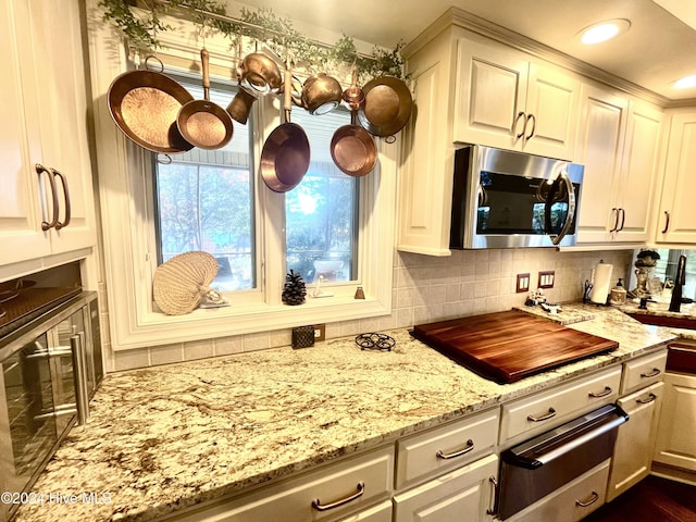 kitchen featuring decorative backsplash, white cabinets, light stone counters, and black stovetop