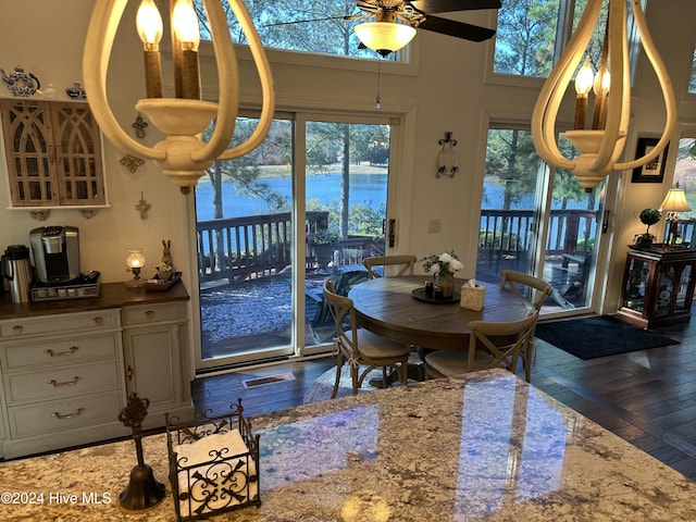 dining space with a water view, ceiling fan, dark wood-type flooring, and a high ceiling