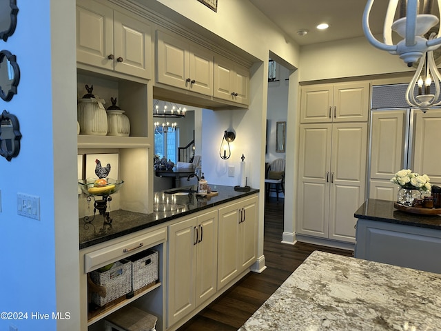 kitchen featuring dark hardwood / wood-style floors, white cabinetry, dark stone countertops, a chandelier, and paneled built in refrigerator