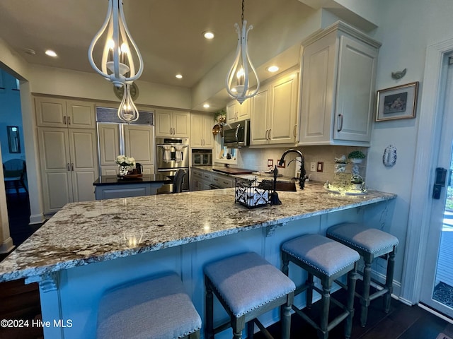 kitchen with tasteful backsplash, hanging light fixtures, dark stone counters, and appliances with stainless steel finishes