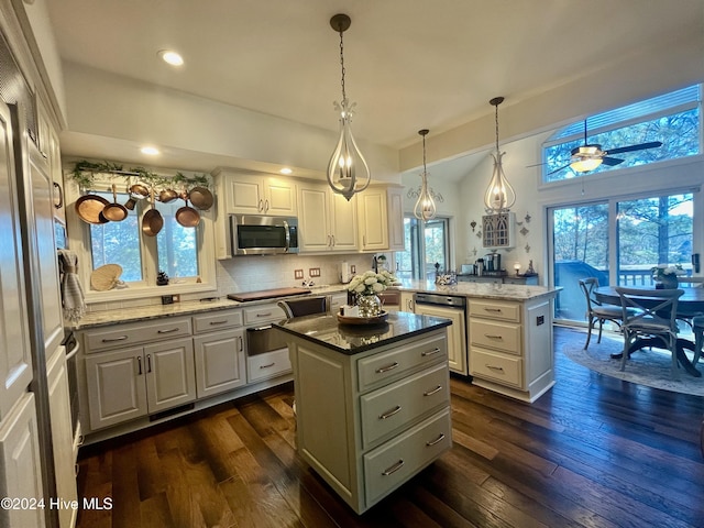 kitchen with a kitchen island, pendant lighting, white cabinets, decorative backsplash, and light stone counters