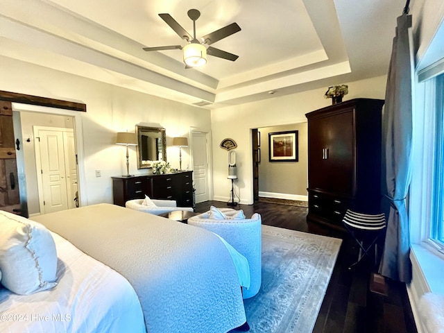 bedroom with dark wood-type flooring, ceiling fan, and a raised ceiling