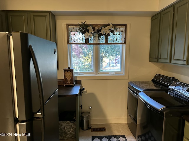 washroom with light tile patterned floors, washing machine and dryer, and cabinets