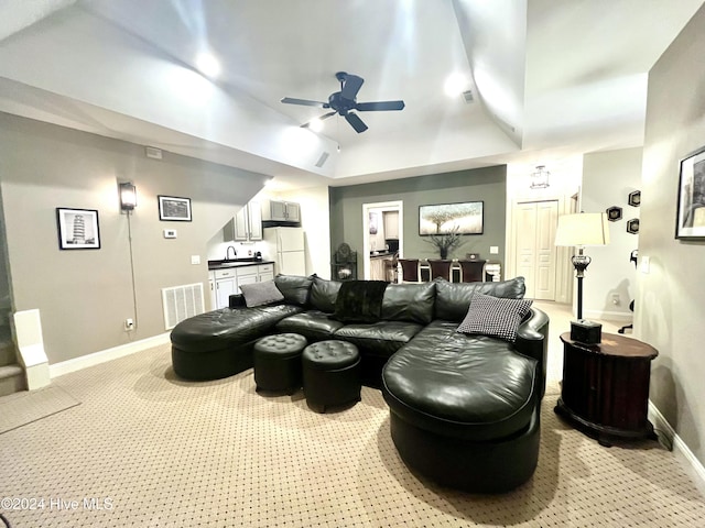 carpeted home theater room featuring a high ceiling, indoor wet bar, ceiling fan, and a tray ceiling