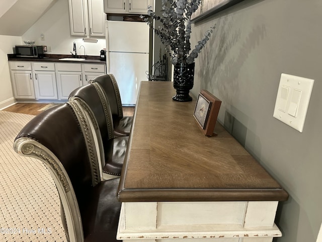 interior space featuring lofted ceiling, sink, and light hardwood / wood-style flooring