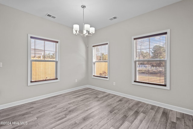 empty room featuring an inviting chandelier and light wood-type flooring