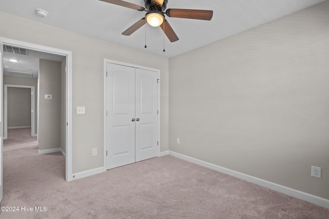 unfurnished bedroom with ceiling fan, light carpet, and a closet