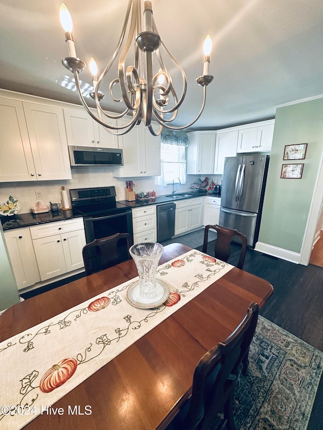 kitchen featuring decorative backsplash, white cabinetry, black appliances, and a notable chandelier