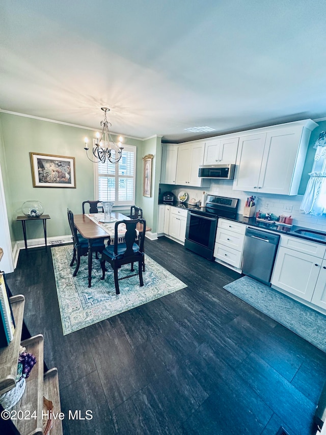 kitchen with white cabinets, dark hardwood / wood-style floors, decorative backsplash, appliances with stainless steel finishes, and a notable chandelier