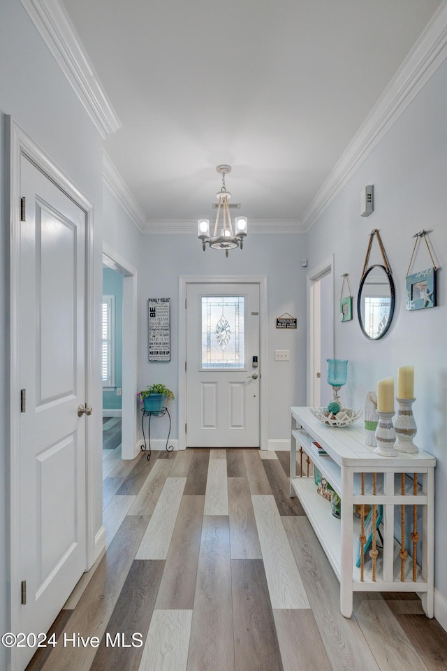 entryway with a chandelier, crown molding, and light hardwood / wood-style floors