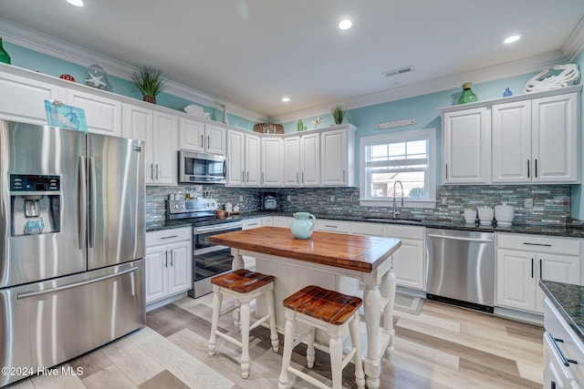 kitchen with white cabinetry, sink, butcher block countertops, appliances with stainless steel finishes, and light wood-type flooring