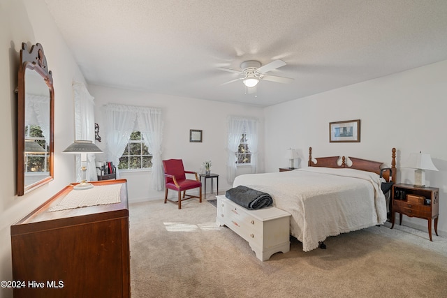 carpeted bedroom with ceiling fan and a textured ceiling