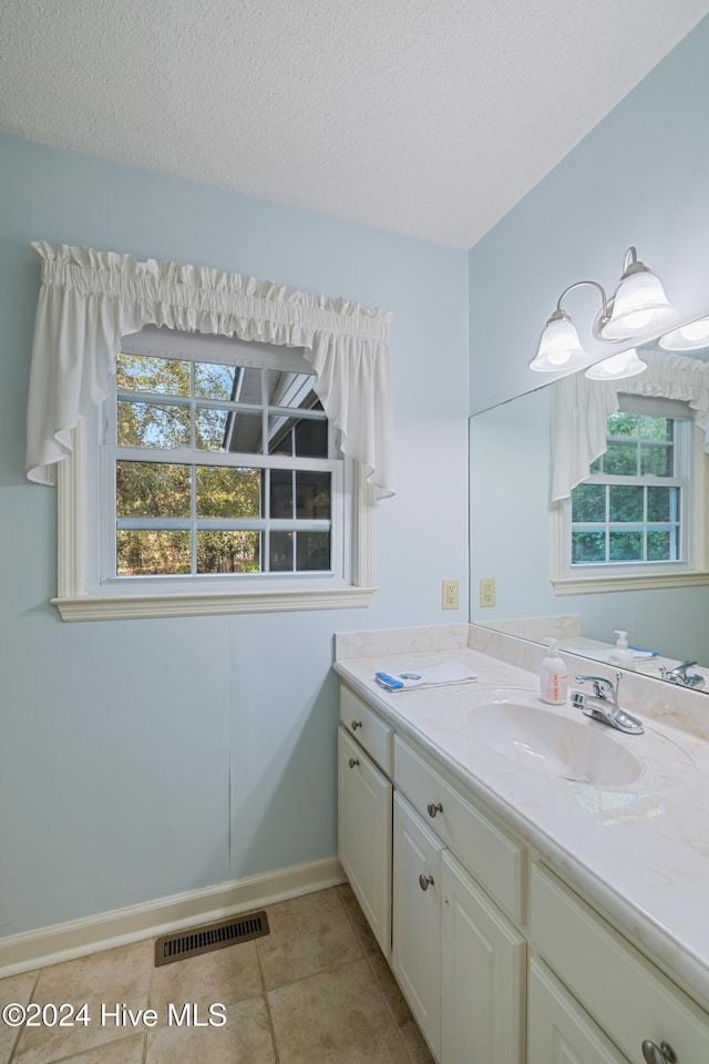 bathroom featuring tile patterned flooring, vanity, and a textured ceiling