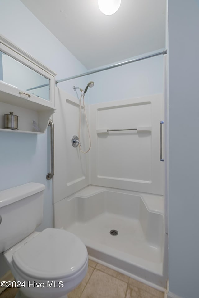 bathroom featuring tile patterned floors, toilet, and walk in shower