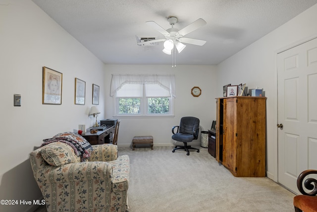 carpeted home office with a textured ceiling and ceiling fan