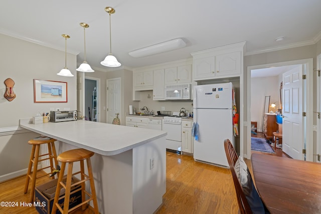 kitchen with a breakfast bar, white appliances, white cabinets, decorative light fixtures, and kitchen peninsula