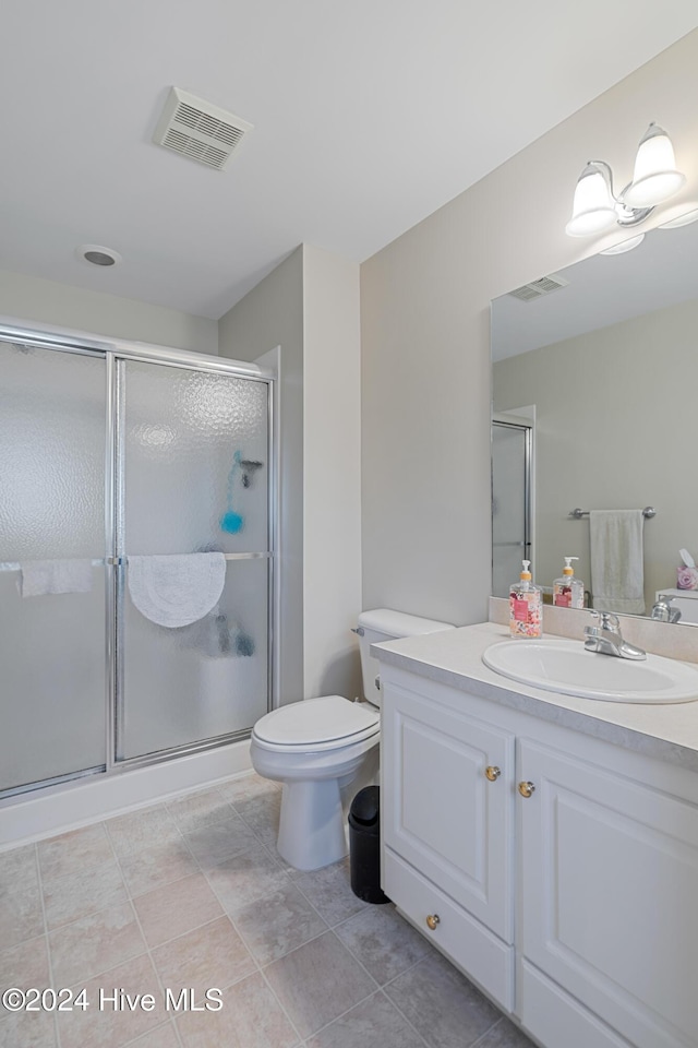 bathroom with tile patterned flooring, vanity, toilet, and a shower with shower door