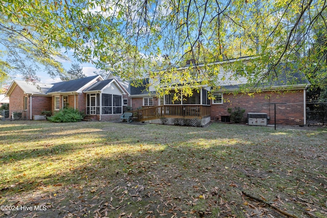 back of property with a sunroom, a yard, and a wooden deck