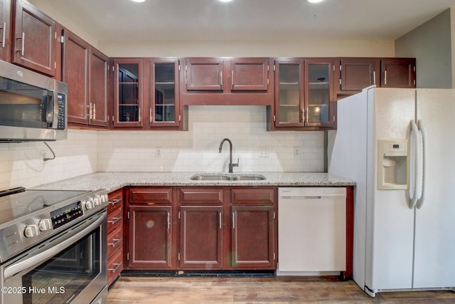 kitchen with light stone countertops, decorative backsplash, stainless steel appliances, and sink