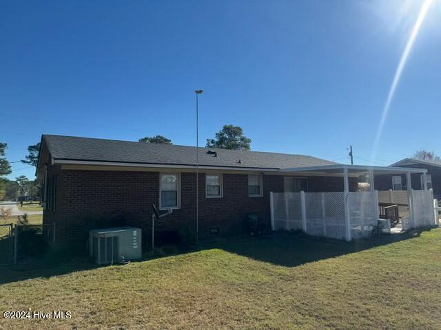 rear view of property with cooling unit and a lawn