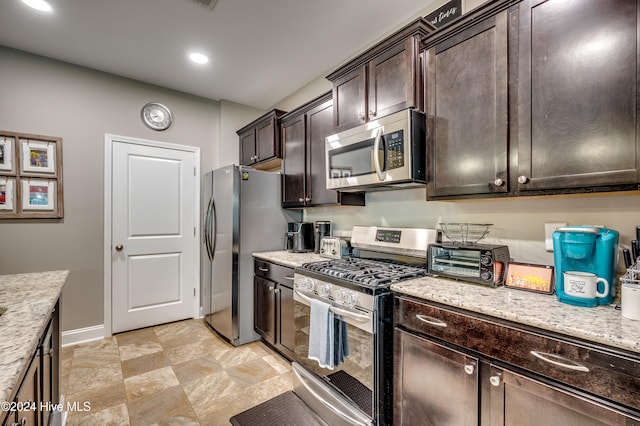 kitchen with appliances with stainless steel finishes, light stone counters, and dark brown cabinets