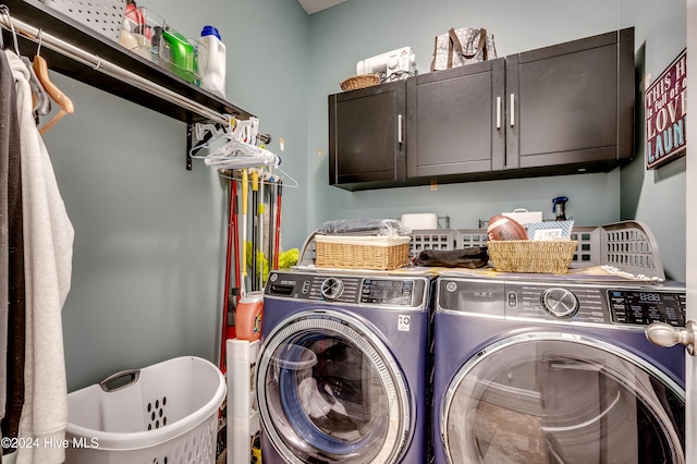 clothes washing area with cabinets and washing machine and clothes dryer