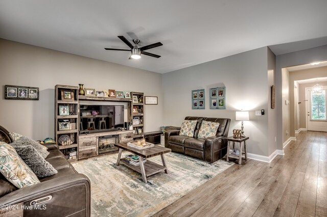 living room featuring ceiling fan, a fireplace, and light wood-type flooring