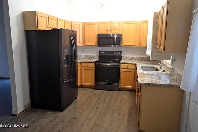 kitchen with light stone countertops, sink, light brown cabinets, dark wood-type flooring, and black appliances