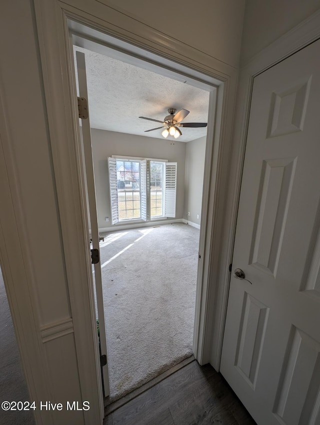 hall featuring a textured ceiling and dark hardwood / wood-style flooring