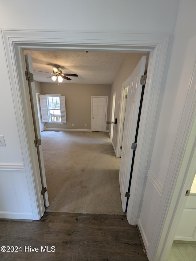 corridor featuring dark carpet and a textured ceiling