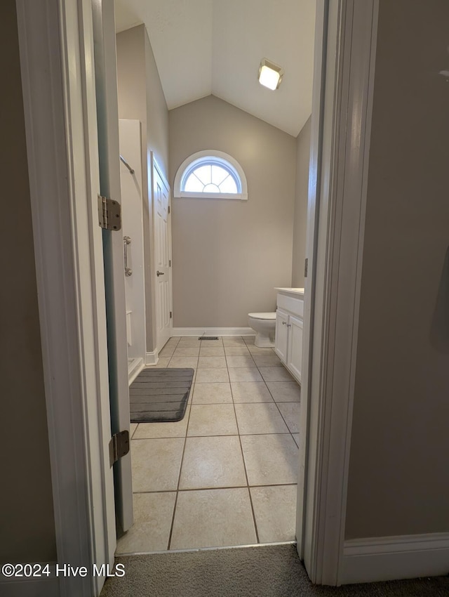 bathroom with tile patterned flooring, vanity, lofted ceiling, and toilet