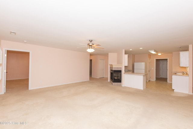 unfurnished living room featuring light carpet, sink, and ceiling fan