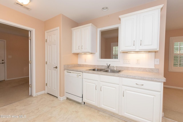 kitchen with white dishwasher, white cabinetry, and sink