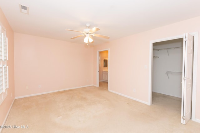 unfurnished bedroom with ceiling fan, light colored carpet, a spacious closet, and a closet