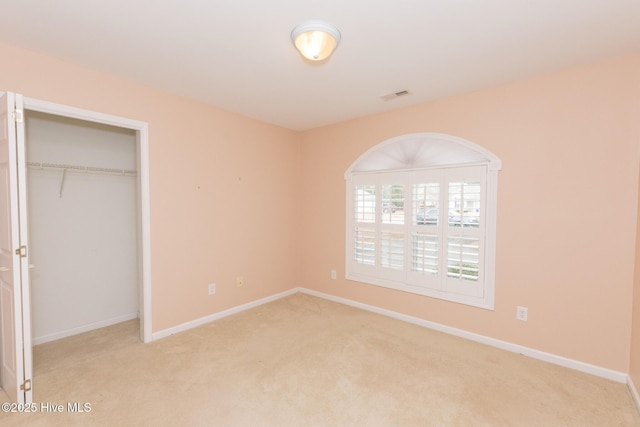 unfurnished bedroom with light carpet and a closet