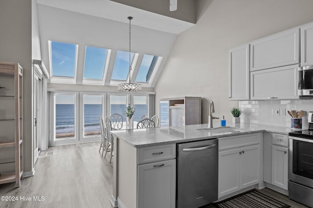 kitchen featuring white cabinets, a water view, sink, kitchen peninsula, and stainless steel appliances