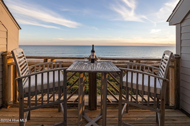 balcony at dusk with a water view and a beach view