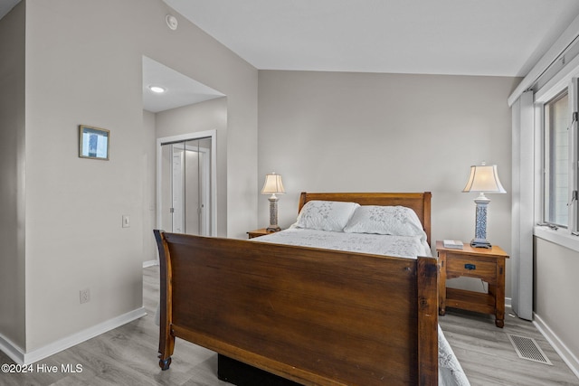 bedroom featuring a closet, light hardwood / wood-style floors, and vaulted ceiling