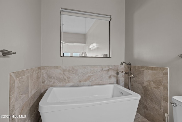 bathroom with a washtub and tile walls