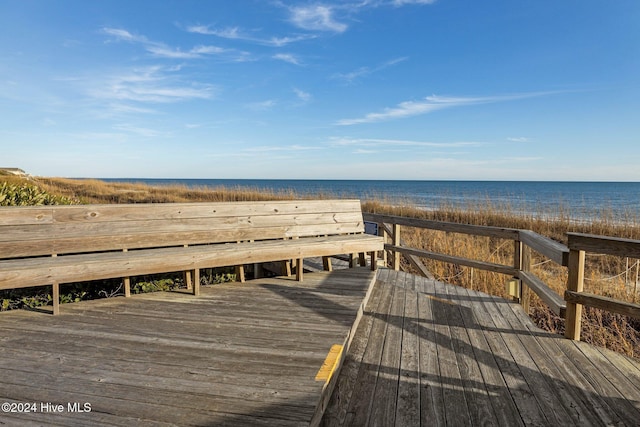 wooden terrace featuring a water view and a beach view