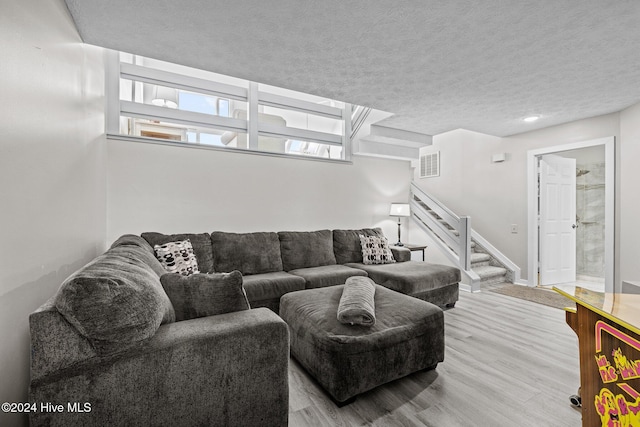 living room featuring light wood-type flooring and a textured ceiling