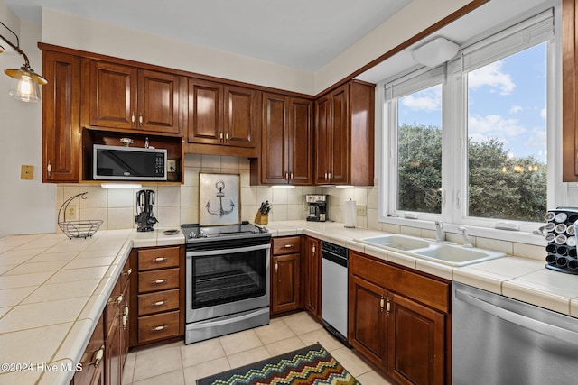 kitchen featuring sink, tasteful backsplash, tile counters, light tile patterned flooring, and stainless steel appliances