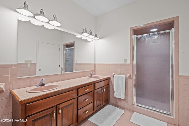 bathroom with tile patterned flooring, vanity, tile walls, and walk in shower